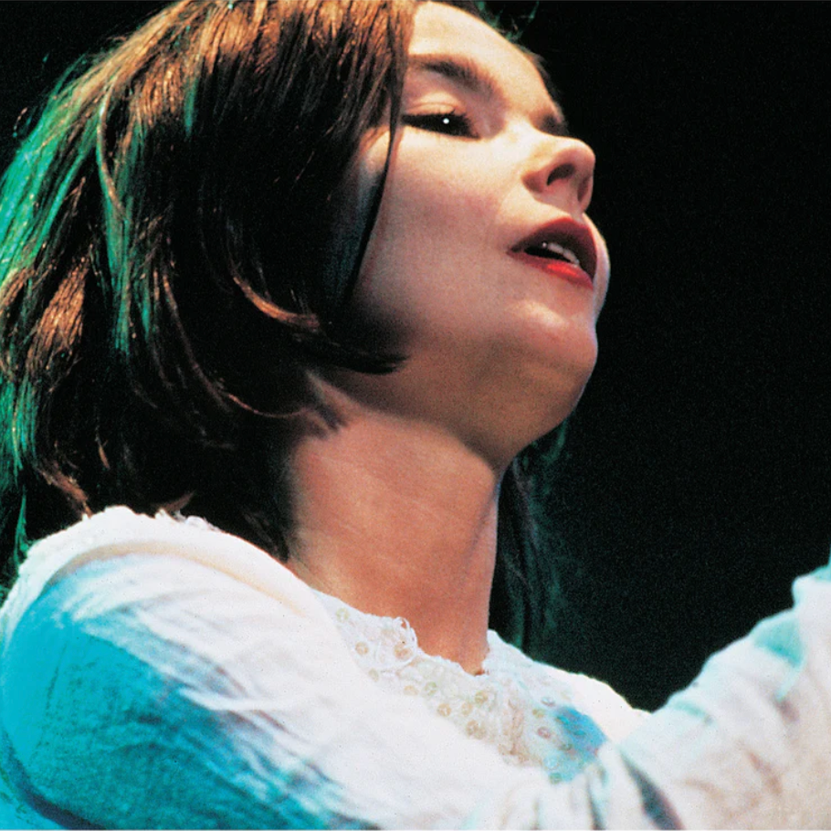 Close-up of a person with green hair and a white outfit against a dark background