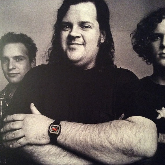 Black and white photo of three people with a focus on the person in the center wearing a watch.